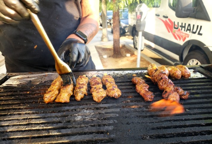 Sam Oum grilling lemongrass beef skewers and twko sausage at Kreung Kitchen