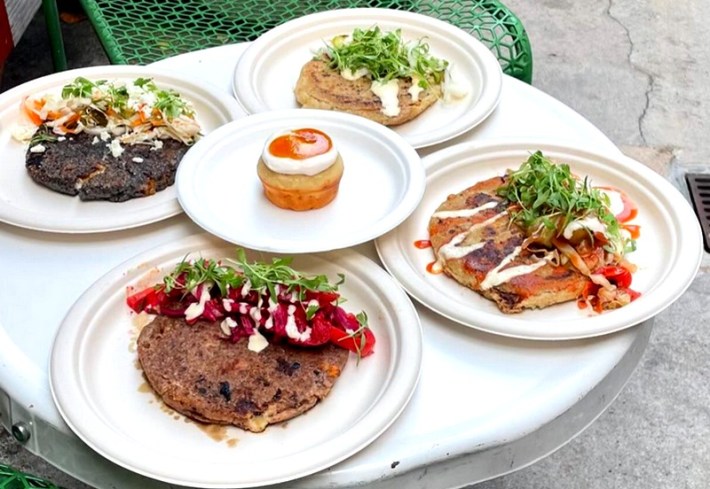 Four different pupusas on white plates ona white table