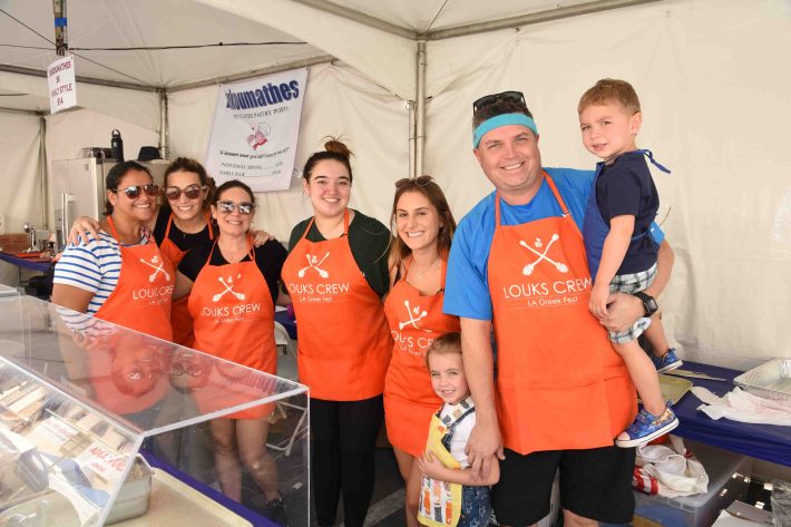 8 members of the Louks crew at L.A. Greek Fest, many wearing orange aprons, photo via L.A. Greek Fest