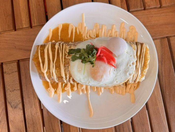 An egg-topped, sauce-drizzled burrito de chilaquiles