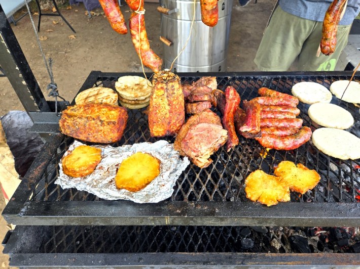 Pineapple, steak, pork belly, sausages, and arepas at Asados To Go.