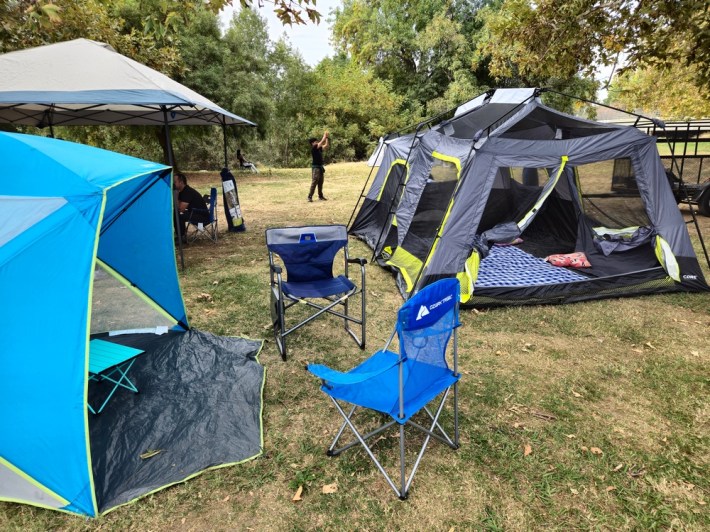 Tents in a park with a boy playing ball in back