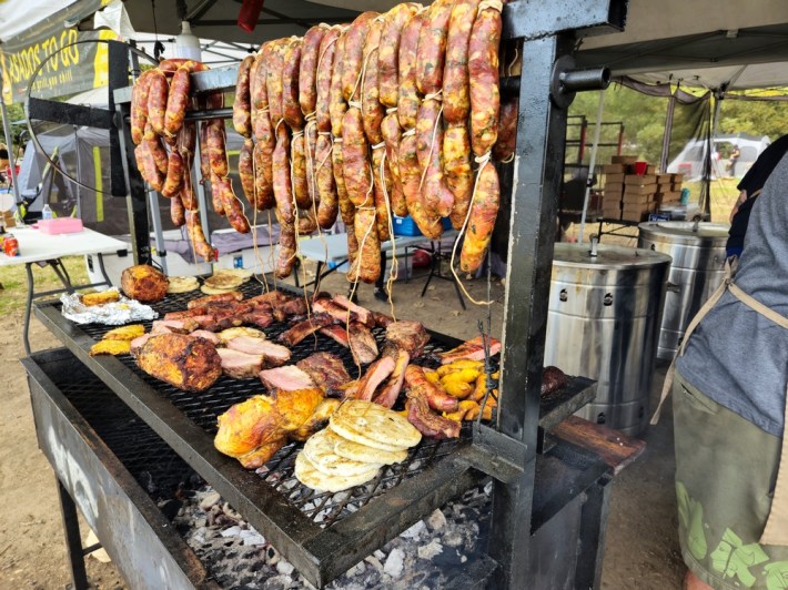 A parrilla full of arepas, plantains, roasted pineapple, pork ribs, trip tip, and sausages.