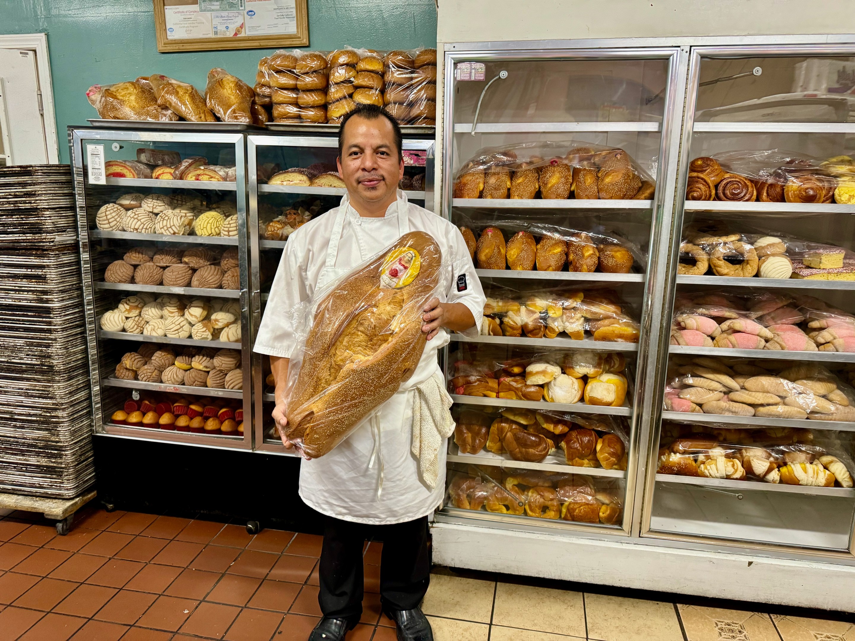 Sinecio Mecinas holding up his pan de muerto. Photo by Javier Cabral for L.A. TACO.