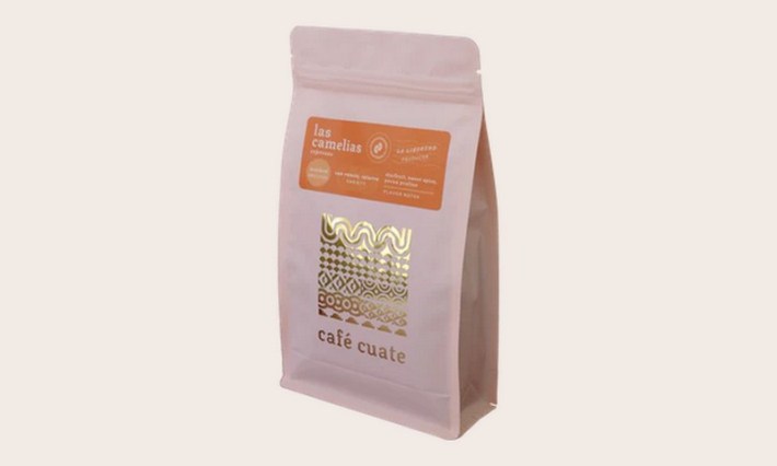 A white bag of coffee with a gold logo and orange label.