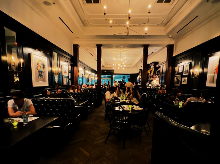 Black leather booths and customers milling inside of The Black Cat in Silver Lake.