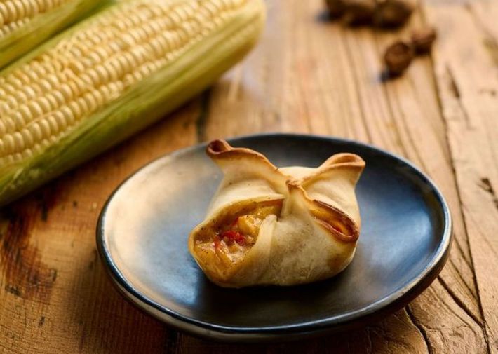 A corn empanada beside an ear of corn.