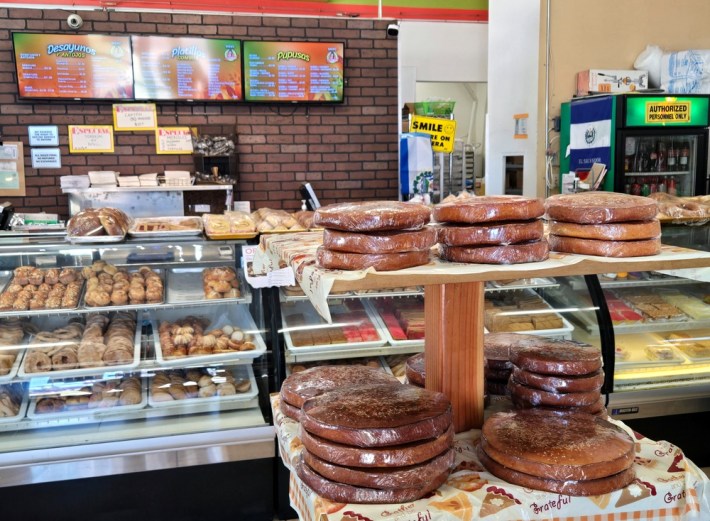 Stacks of Salvadoran quesadillas at La Usuluteca, in front of cases of sweets and pastries.