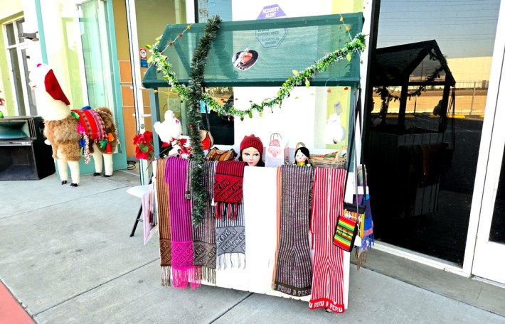 A display of textiles with a stuffed alpaca in back