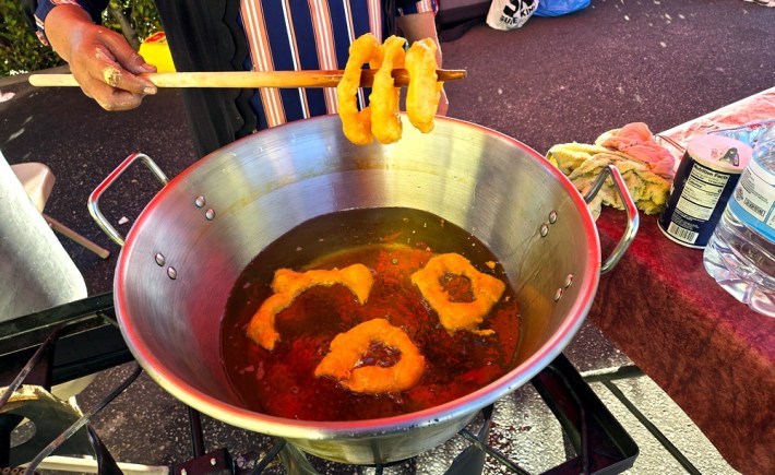 Peruvian donuts (picarones) being lifted from hot oil