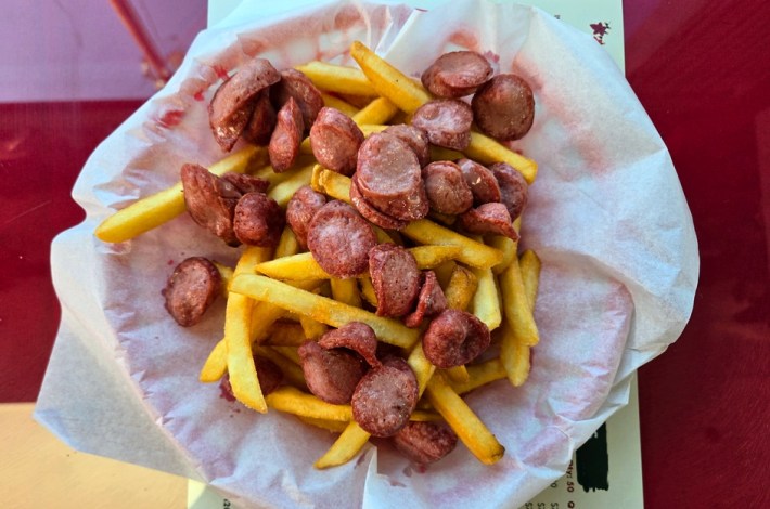 A plate of fries covered in sliced hot dogs.