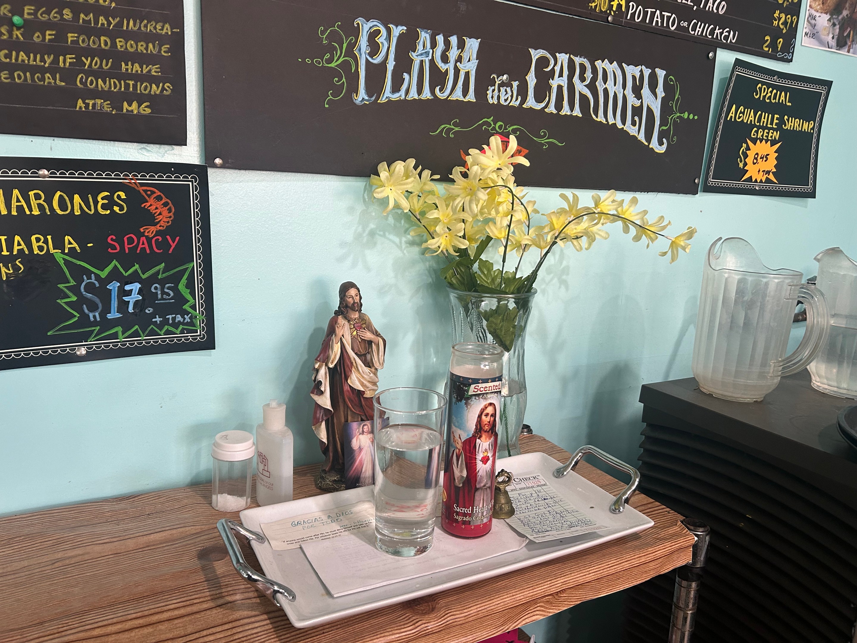 An altar with flowers, a candle, and a saint at Playa del Carmen restaurant in Pasadena