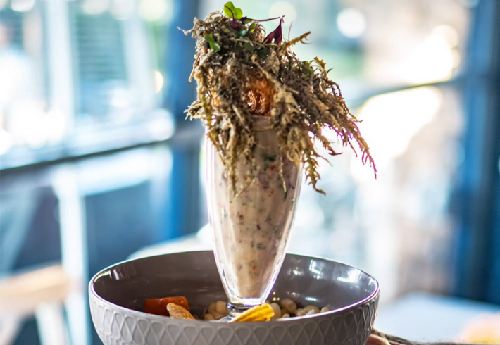 The Hangover: crispy calamari in a bath of leche de tigre, with striped bass, Peruvian corn, and more., in a tall glass.
