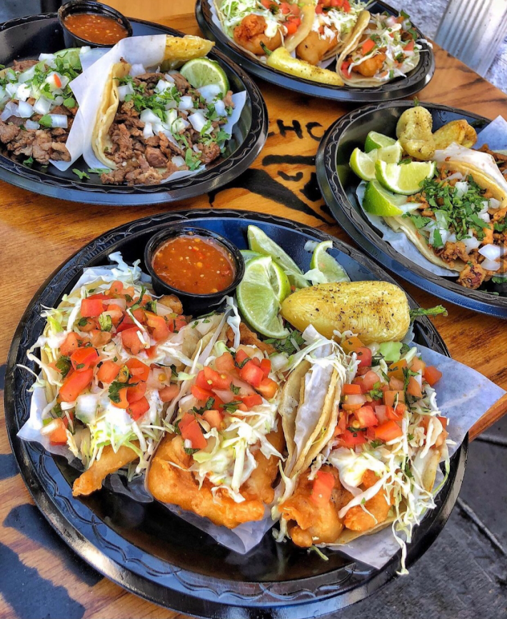 Taco Nazo's famous fish tacos served on a plate with red salsa and a Anaheim chile.