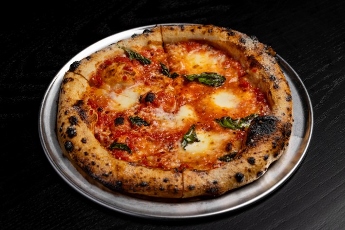 A margherita pizza on a round silver tray at Downtown Dough.