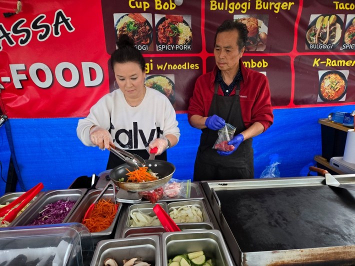 Savannah Lee putting vegetables in a pan, while Ken Lee marinates his bulgogi at their food stand, Assa.
