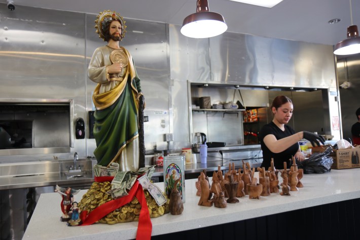 San Judas Tadeo statue sits on the counter of a taqueria.