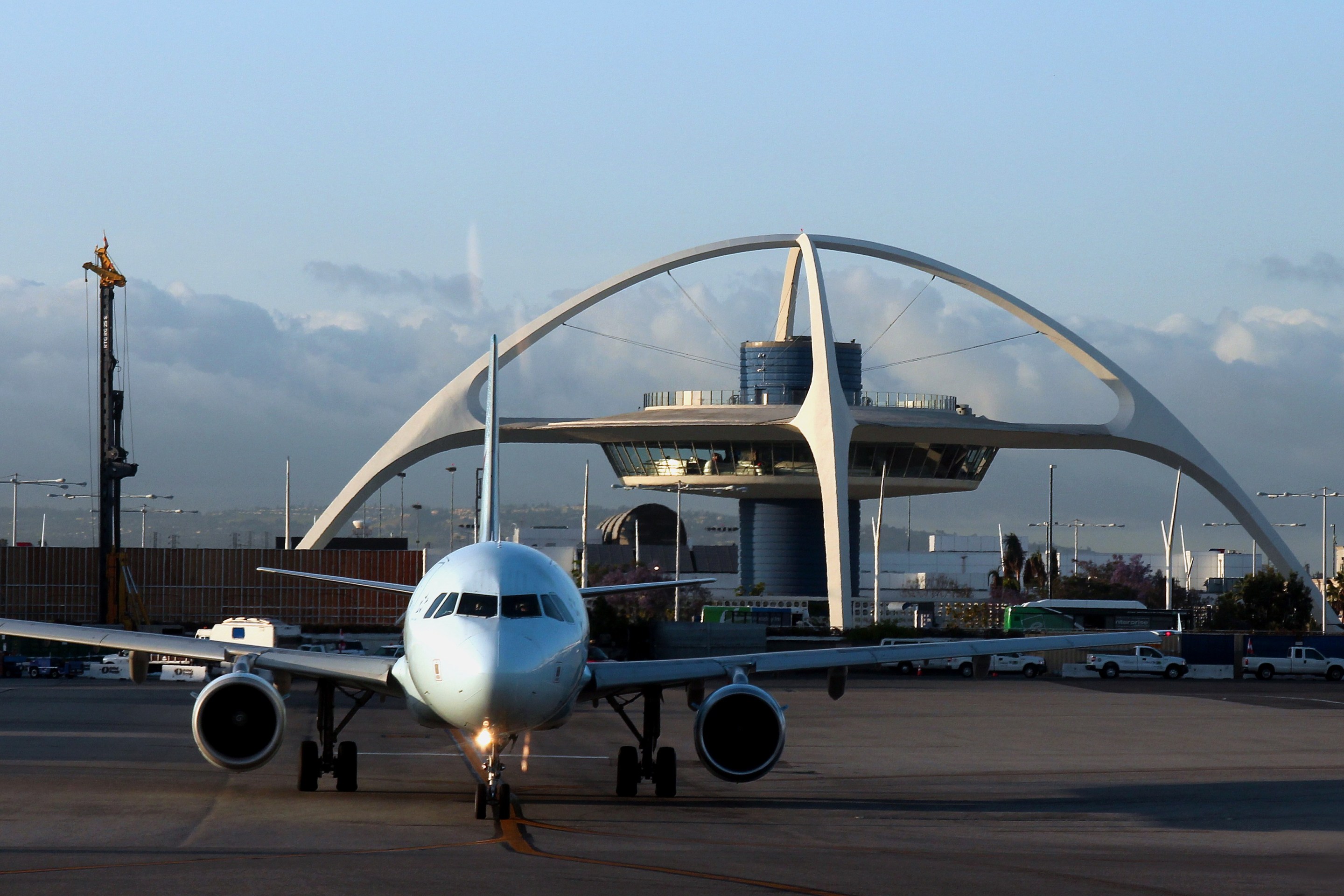 A wide shot of a plane parked on the tarmac of Los Angeles International Airport.