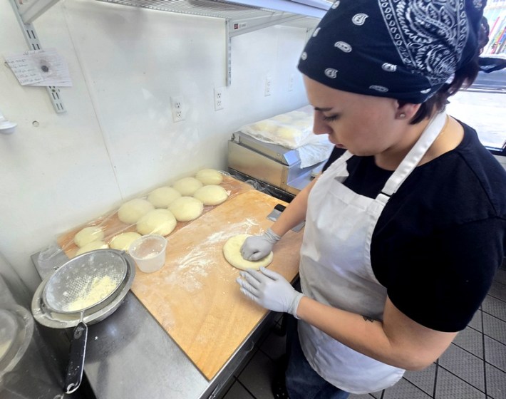 Baker Nini Qutidze, her hair behind a black kerchief, flattening a ball of dough at Saqartvelo Georgian Cuisine in Van Nuys.