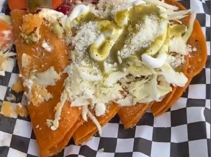 Four tacdos de canasta covered in salsa verde, crema, cabbage, and powdered cheese