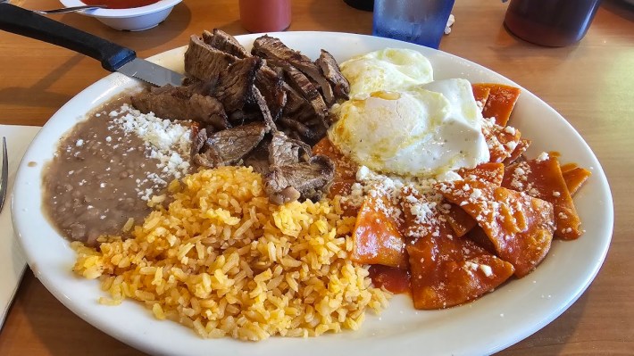 Chilaquiles rojos, with mexican rice, beans with cheese, grilled steak and two sunny side up eggs.