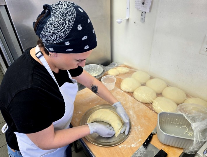 Baker Nini Qutidze, her hair behind a black kerchief,pushes in the edges of crescent-shaped pastry dough at Saqartvelo Georgian Cuisine in Van Nuys.