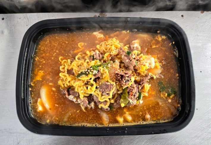 A black plastic tray with ramen, red broth, and bulgogi at Assa.