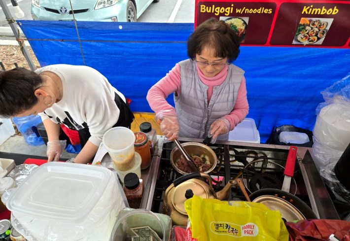 Two women cook Korean food over a four-burner stove at Assa in Venice.