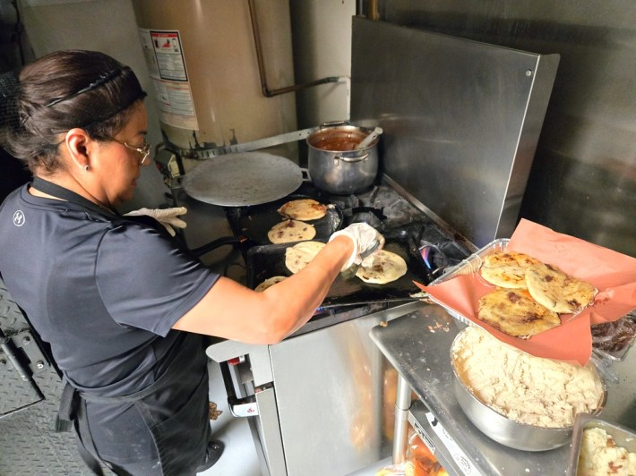 Chef Annabel Ramirez presses a spatula on one of many pupusas spread across her griddle.