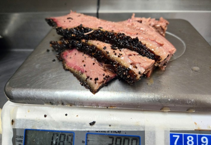 Three slices of brisket being weighed out for an order on a digital scale.