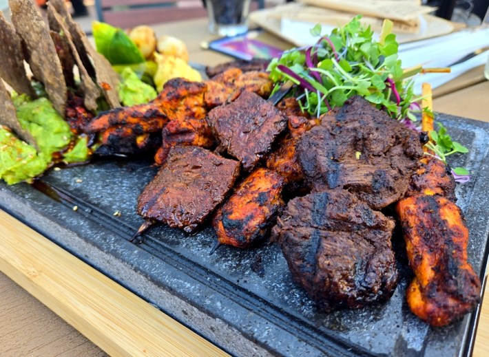 Ancho chile beef and chicken skewers on a lava stone.