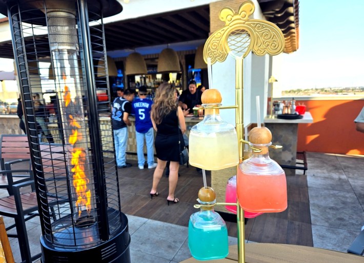 A heat lamp on a rooftop bar next to a Patron-branded margarita tree.