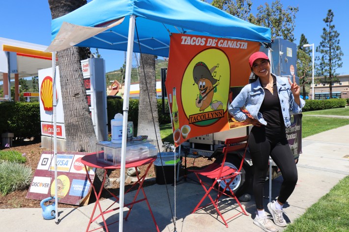 Co owner of Tacollynn psoing in front of her stand.