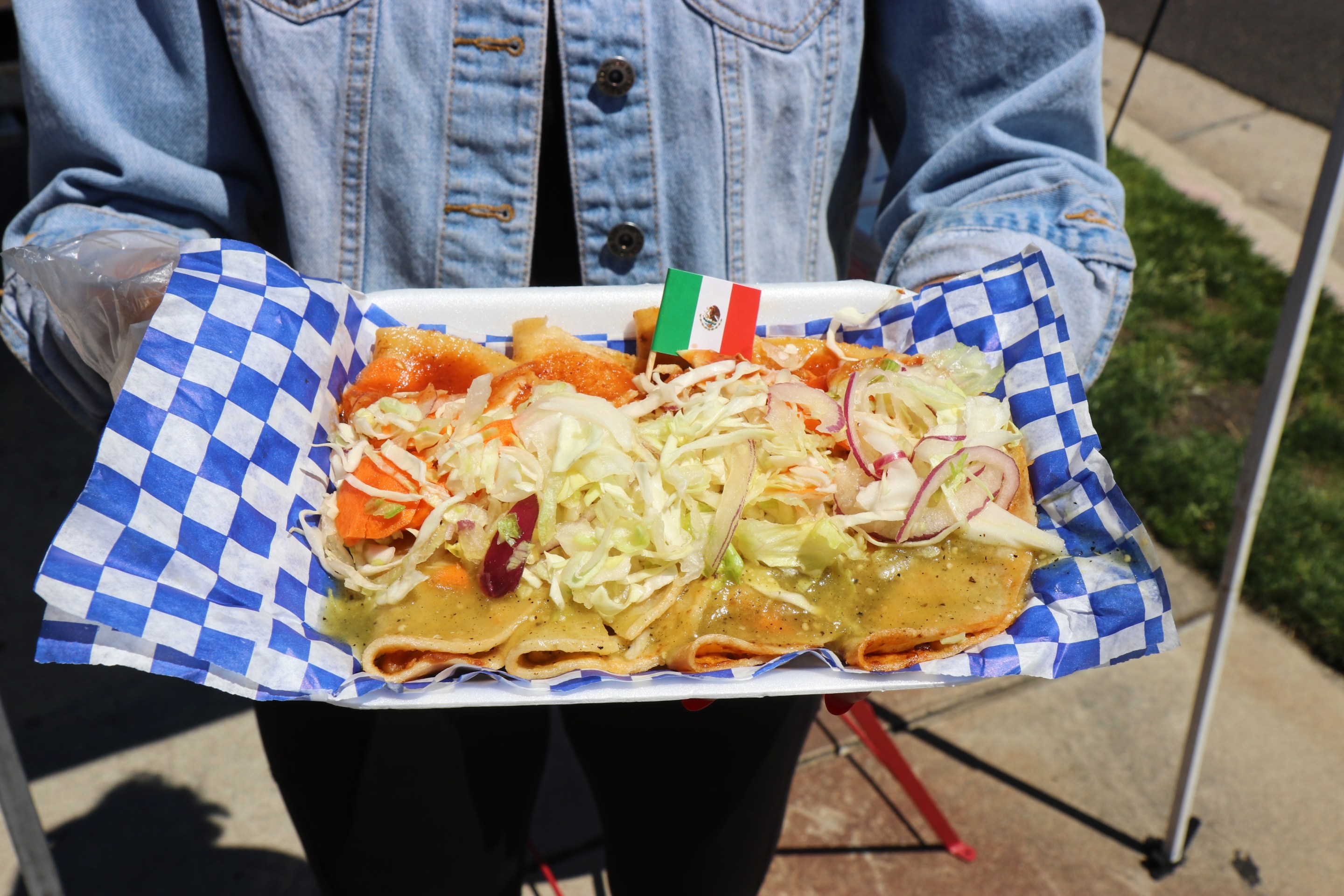 An order of tacos de canasta topped with a mix of shredded lettuce, purple onion and pickled carrots. And dressed with both green and red salsa.