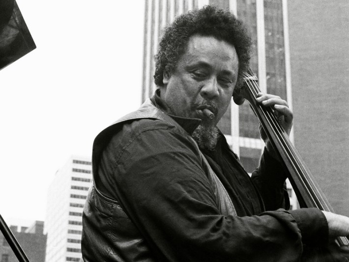Charles Mingus in Lower Manhattan, with a cigar stub in his mouth as he plays the upright bass