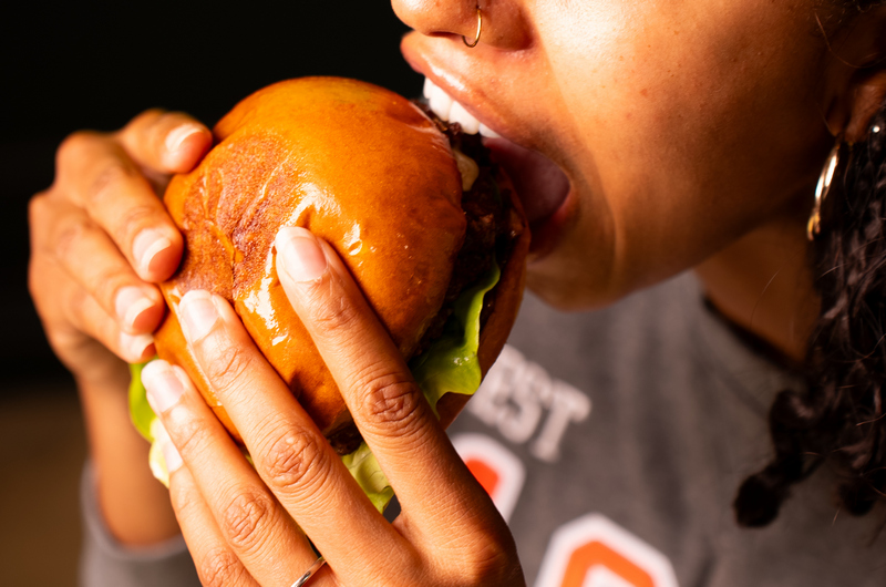 A woman prepares to take a bite out of a burger