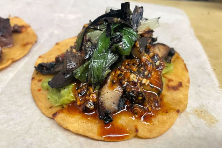 Mushroom taco with confit garlic-infused tortilla, gluten free soy-marinated portobello mushroom topped with salsa macha and a charred scallion.