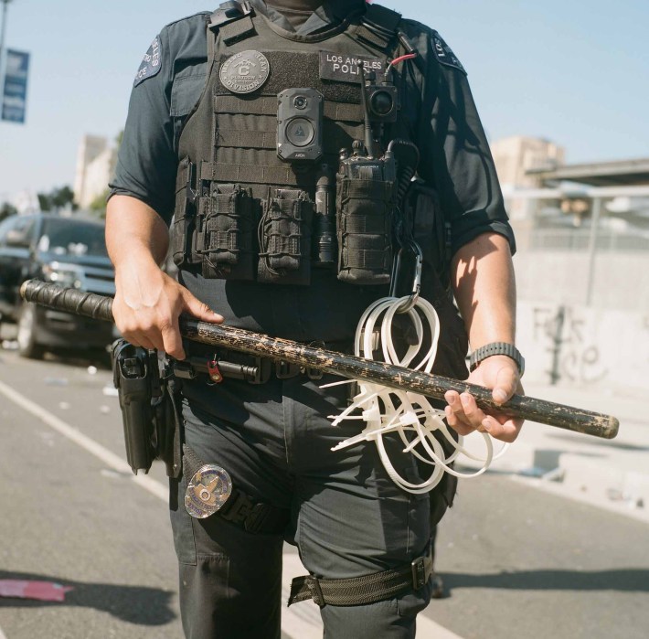 A police officer's torso, showing zip ties, a gun, and a radio