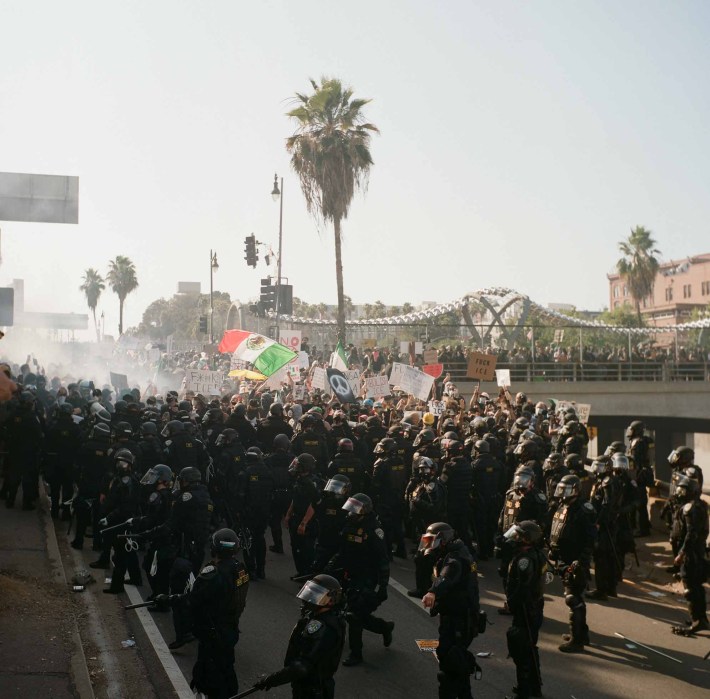A large crowd of riot police in helmets guarding a freeway entrance