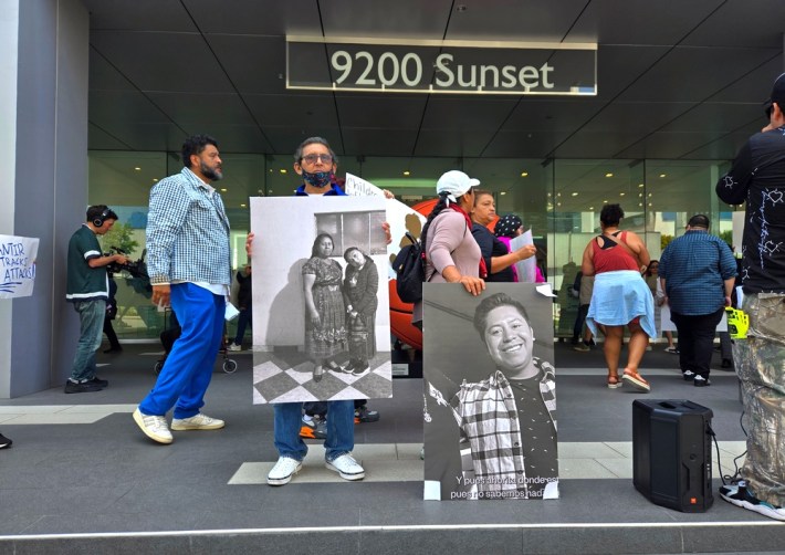 Protestors on the stairs of a high-rise building holding up black-and-white photographs of loved ones
