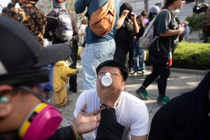 A man has his eyes sprayed with water, to relieve the effects of encountering tear gas