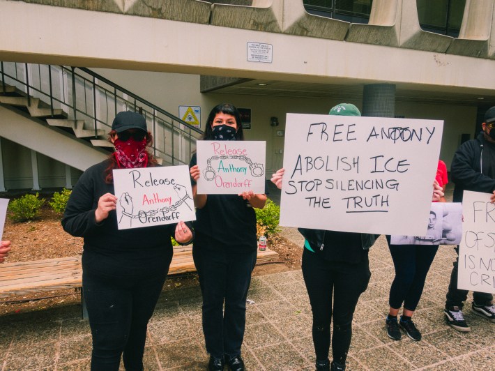 3 supporters of journalist Anthony Orendoff holding up signs pressing for his release
