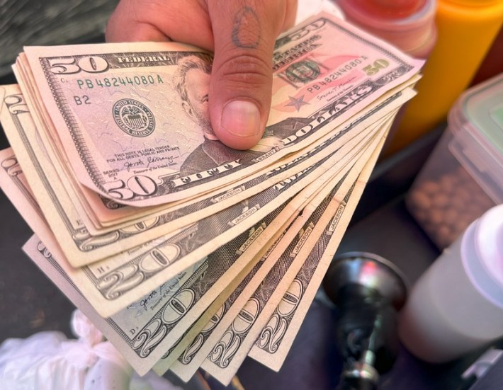 Bills of U.S. currency being given from someone's hand