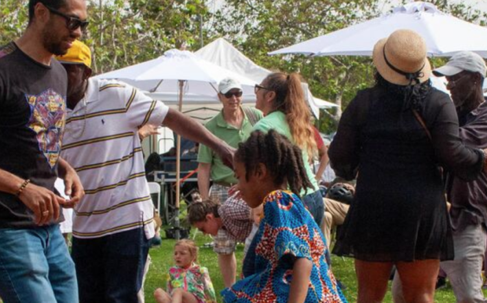 Family and friends revel in a park with white umbrellas in the back