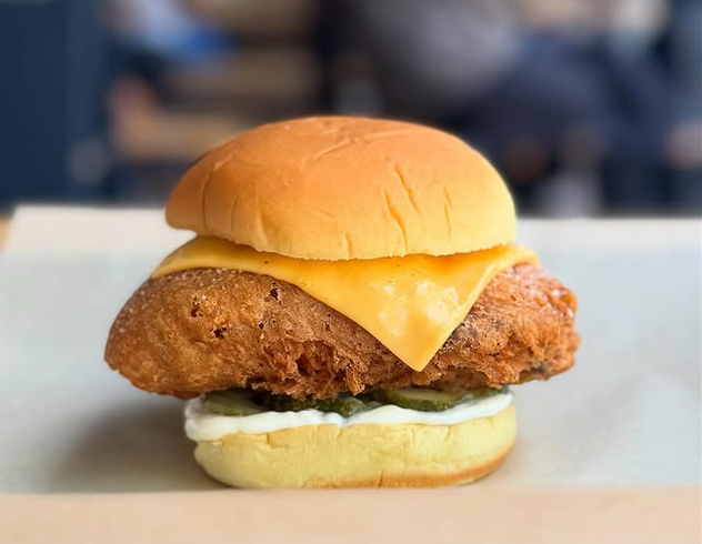 A battered and fried fish sandwich with a slice of cheese melting in the middle.