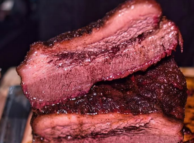 Looking inside two slabs of smoked brisket to see the pink-red interiors