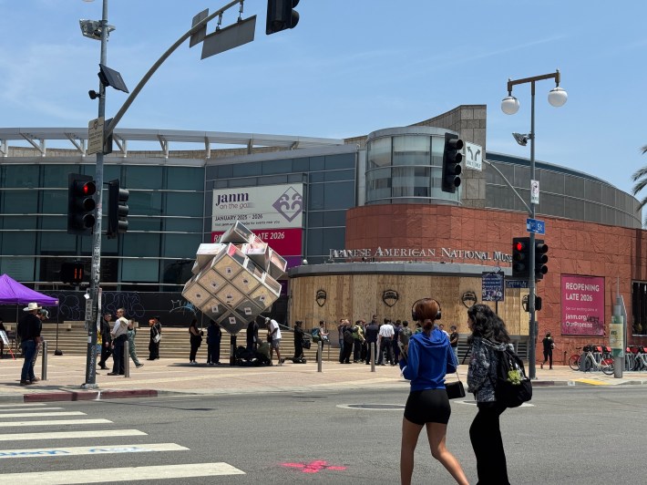Volunteers scrubbing graffiti off of JANM in Little Tokyo, as two girls walk in the foreground