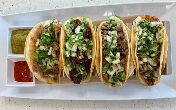 Four tacos in a row, including a classic beef taco, pulled braised beef taco, spicy galbi beef rib taco and beef bulgogi taco.