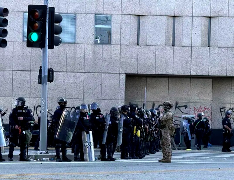 Los Angeles police with shields, one in camo, standing in Downtown L.A.