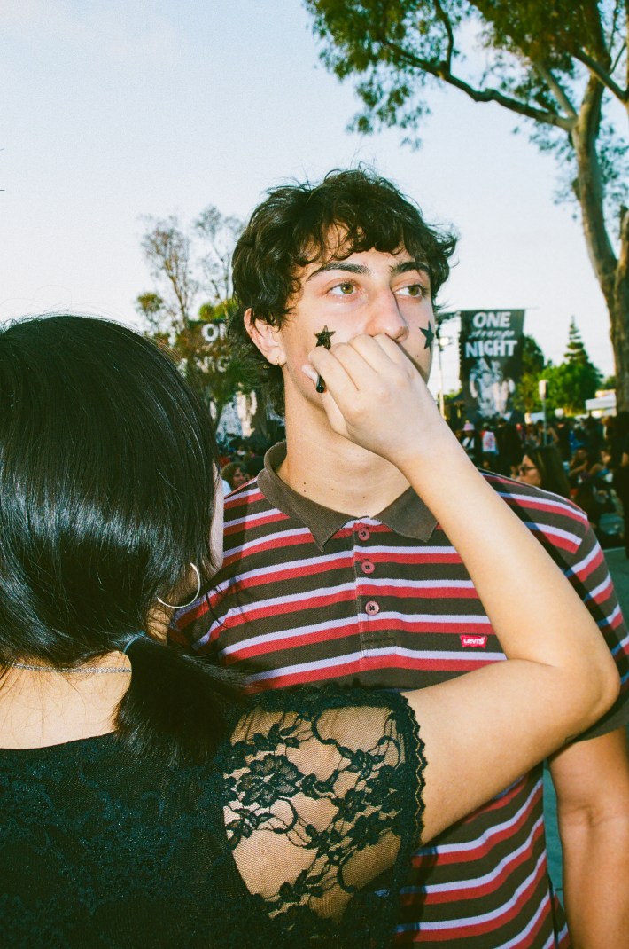 A fan paints another fan's face.